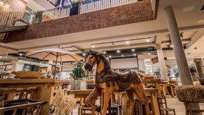 Um interior espaçoso com teto alto, claraboia e escultura de um cavalo de madeira.