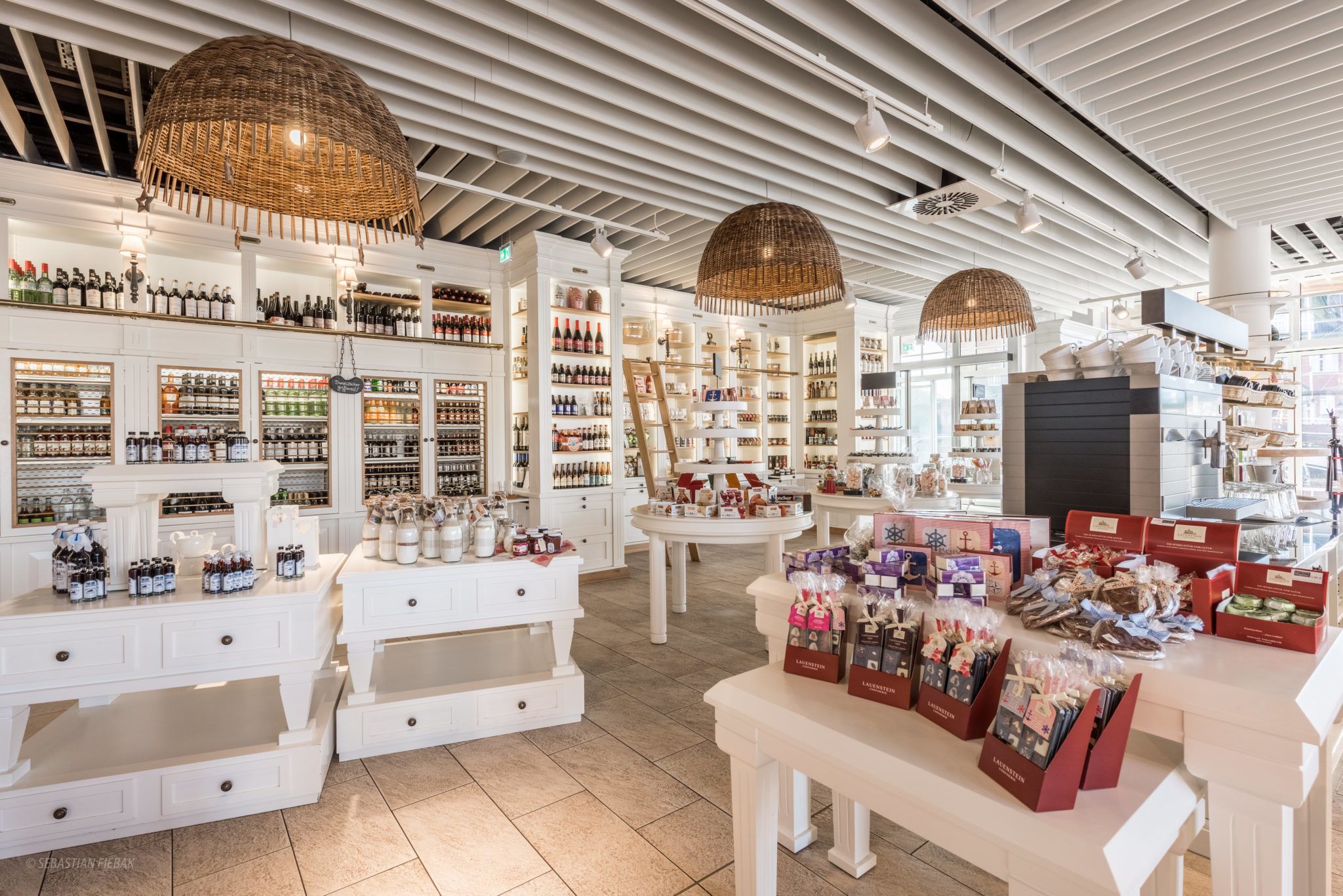 A well-lit store with shelves of various products, including bottles and boxes, and a display area with items on tables.