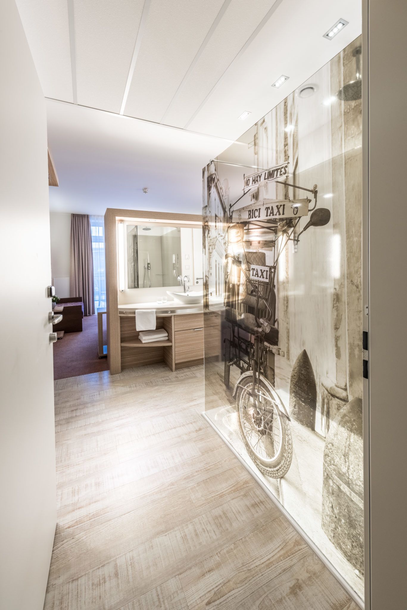A modern bathroom with a large mirror, wooden vanity, and a bicycle mounted on the wall.