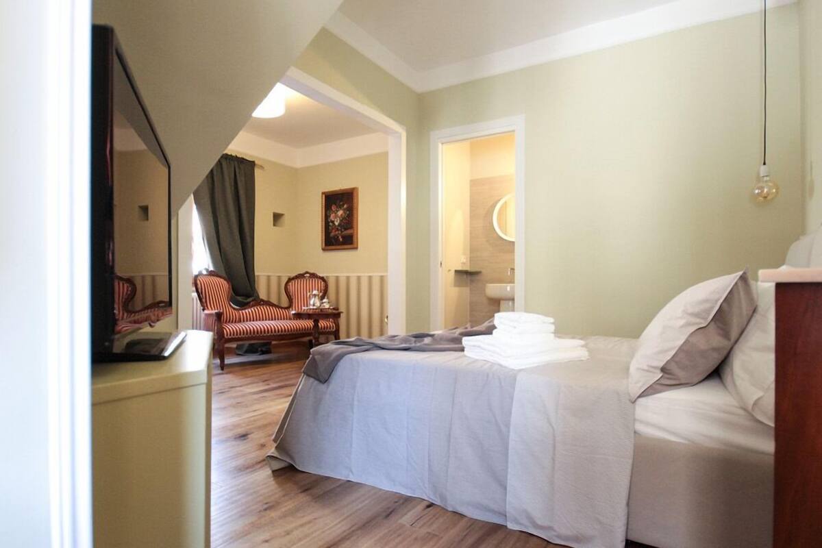 Een hotelkamer met een bed, een stoel, een bureau en een spiegel.