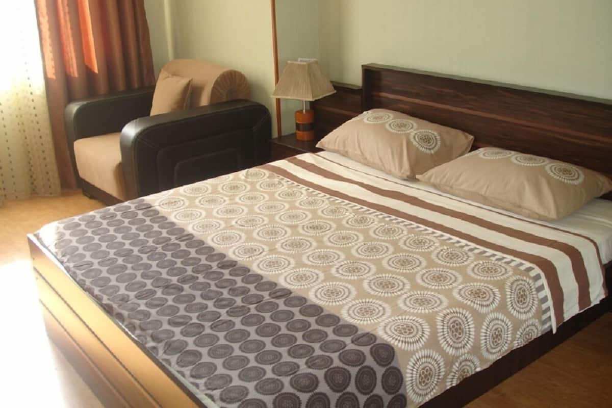 Ein Hotelzimmer mit einem Bett, einem Sessel, einer Lampe und Vorhängen.