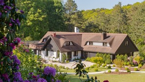 A large house with a sloped roof, surrounded by a well-maintained garden and trees. - Hotel Spa Les Pins De César (Saint-Jouin-Bruneval)