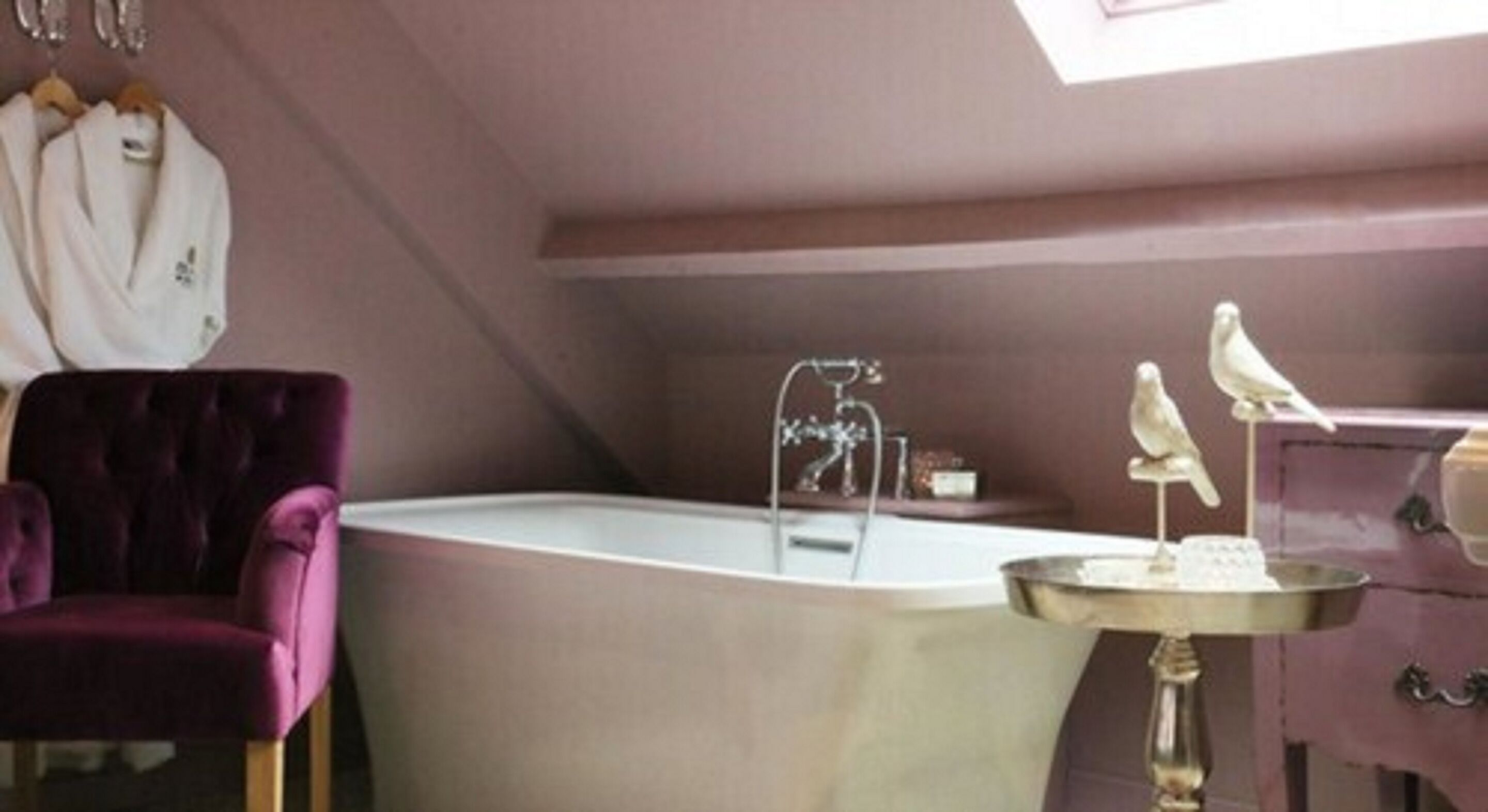 A bathroom with a bathtub, a vanity with a mirror, and a chair.