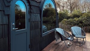 A wooden deck with two chairs and a door. - Hotel Spa Les Pins De César (Saint-Jouin-Bruneval)