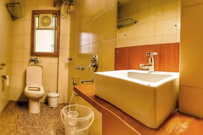 A bathroom with a toilet, sink, and window. - Hotel Samraj (Mumbai)