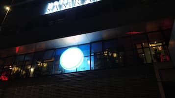 A building with a sign that reads "SAMRAJ" and a large illuminated circular sign below it.