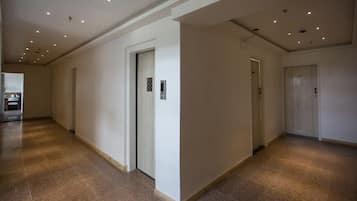 A spacious, well-lit hallway with multiple doors and a tiled floor.