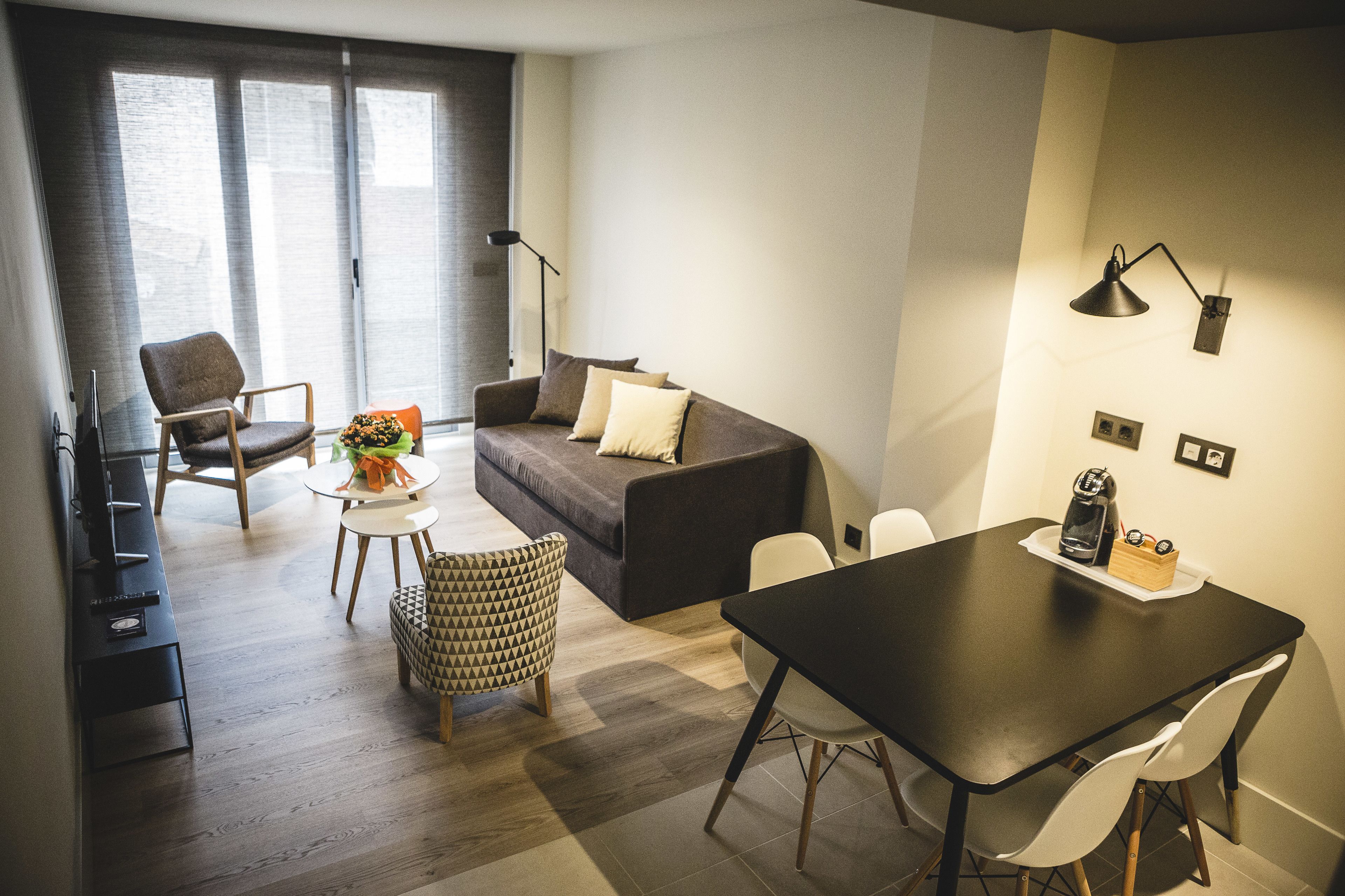 Una sala moderna con sofá, mesa de comedor y cafetera.