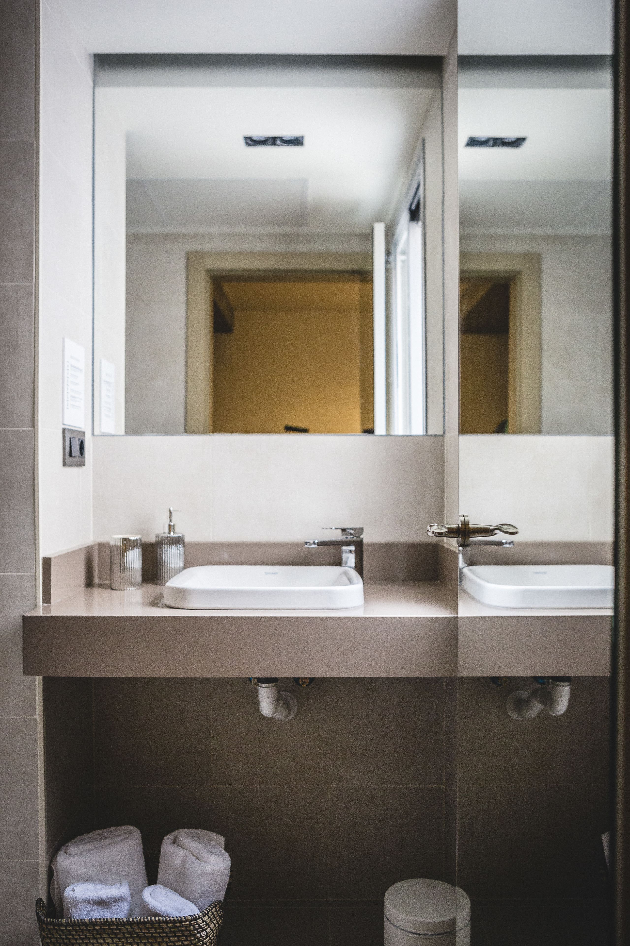 A modern bathroom with two sinks, a large mirror, and a towel rack.