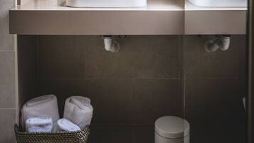 A modern bathroom with two sinks, a large mirror, and a towel rack.