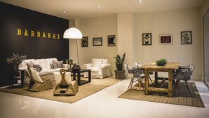A modern interior with a sofa, chairs, a dining table, and a wall with the name 'BÁRBARA'.