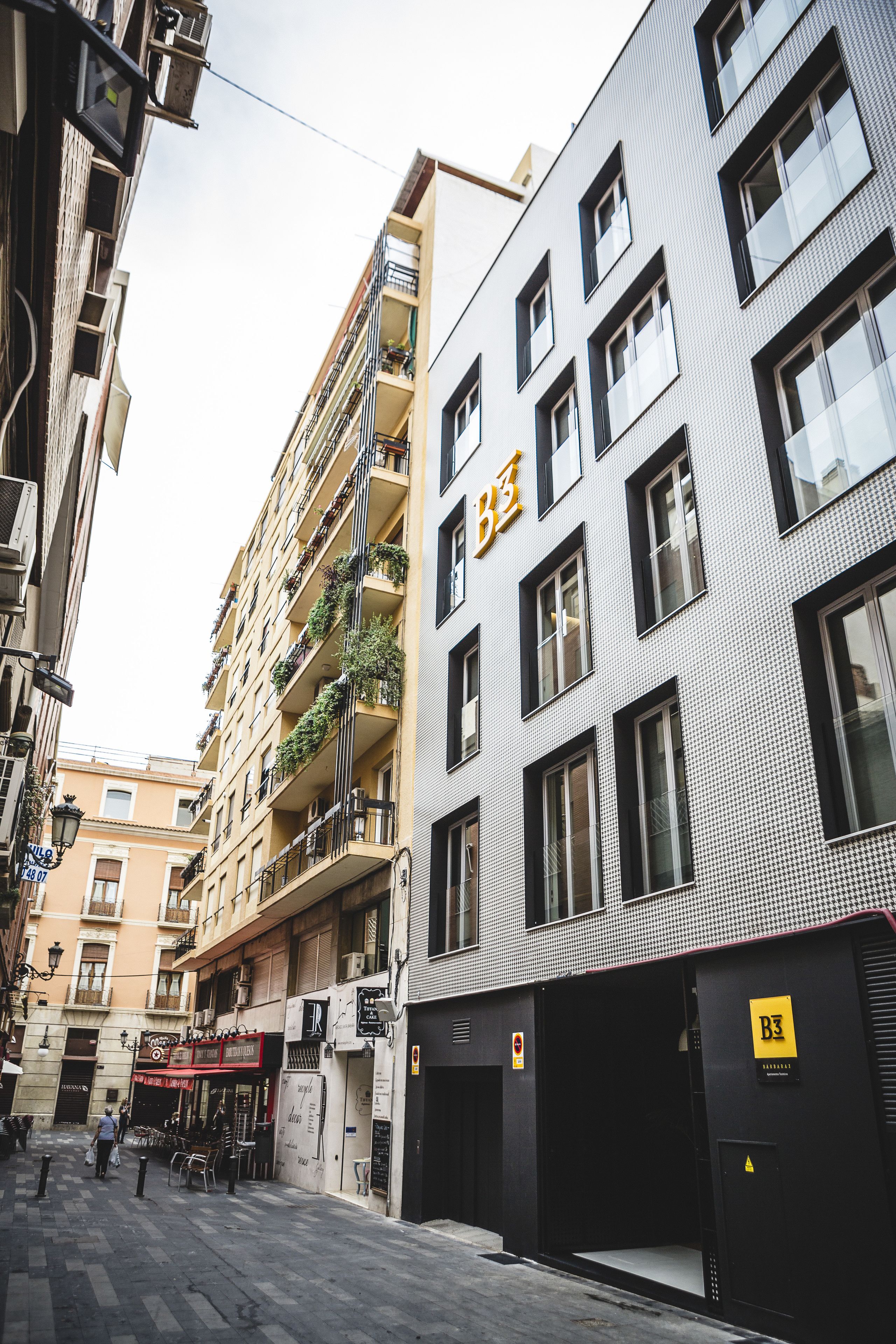 A multi-story building with balconies, a storefront, and a garage entrance.