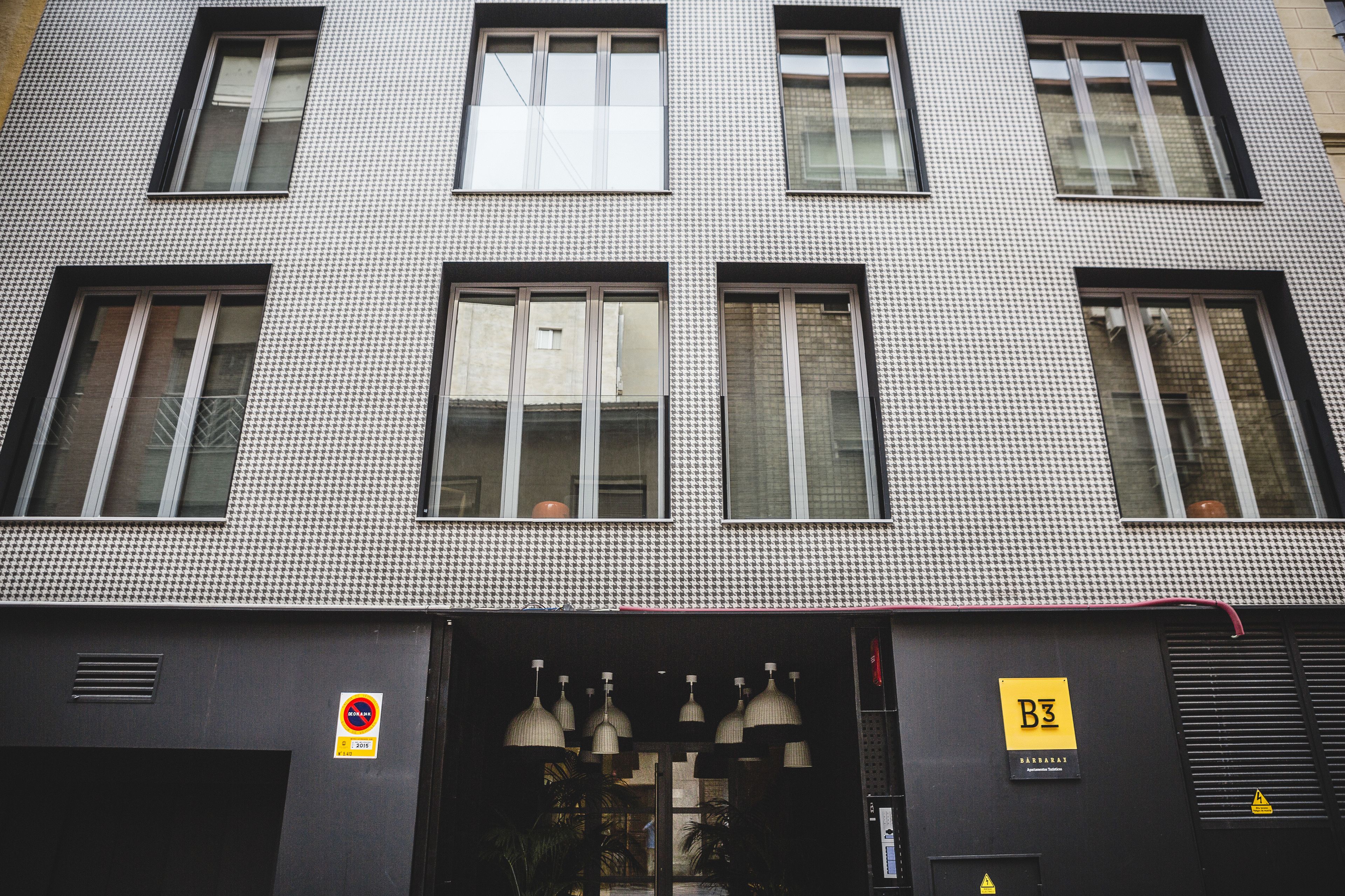 Ein Gebäude mit einer Hundszahn-Fassade, zahlreichen Fenstern und einem Schild, das ein Parkverbot anzeigt.