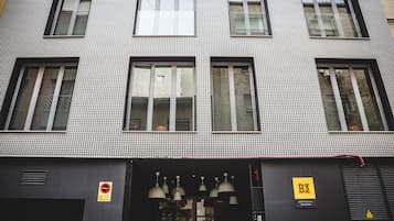 Un edificio con fachada estampada con diseño pata de gallo, varias ventanas y un cartel que indica zona prohibido estacionar.