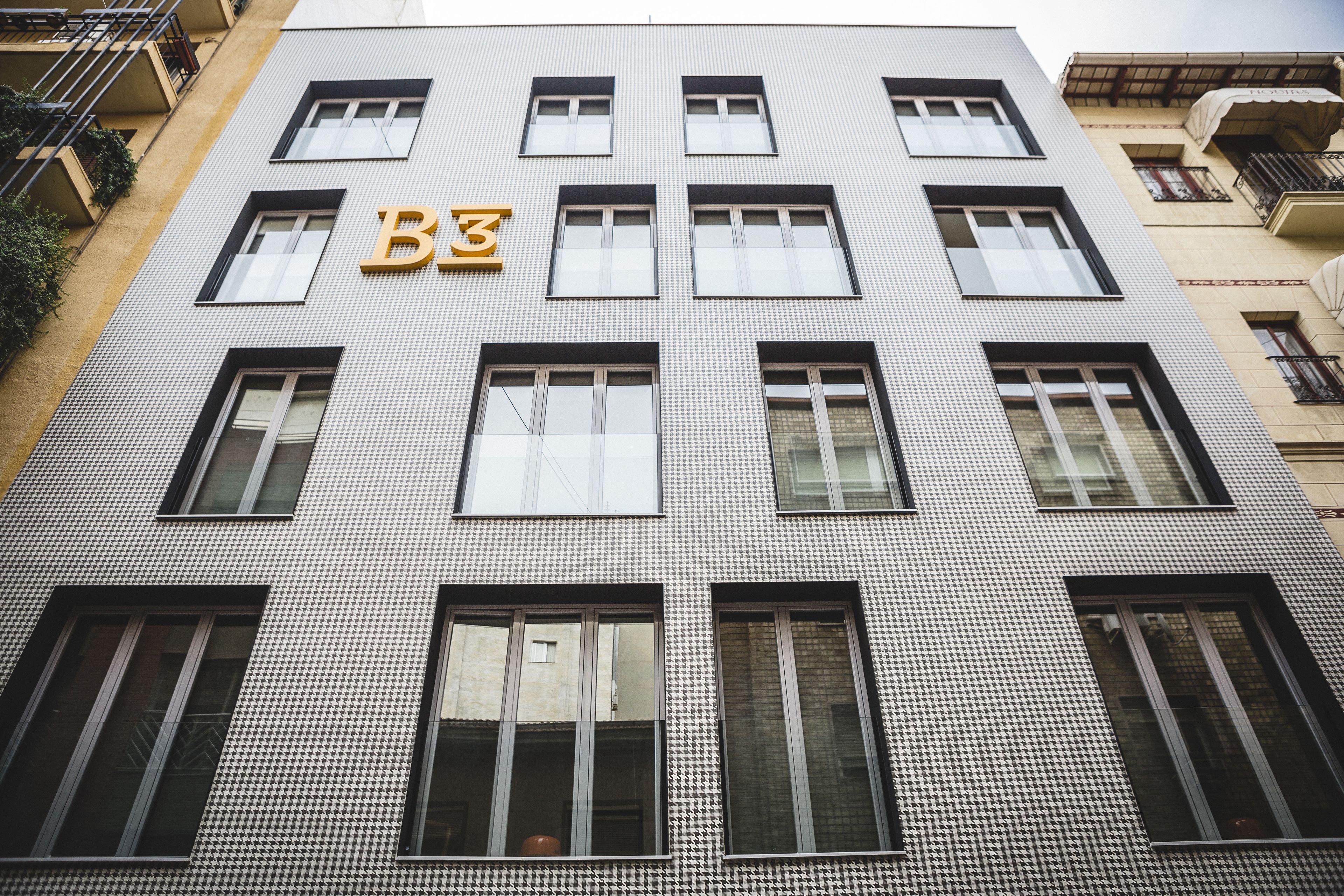 A building with a houndstooth pattern facade, multiple windows, and a prominent 'B3' sign above the entrance.