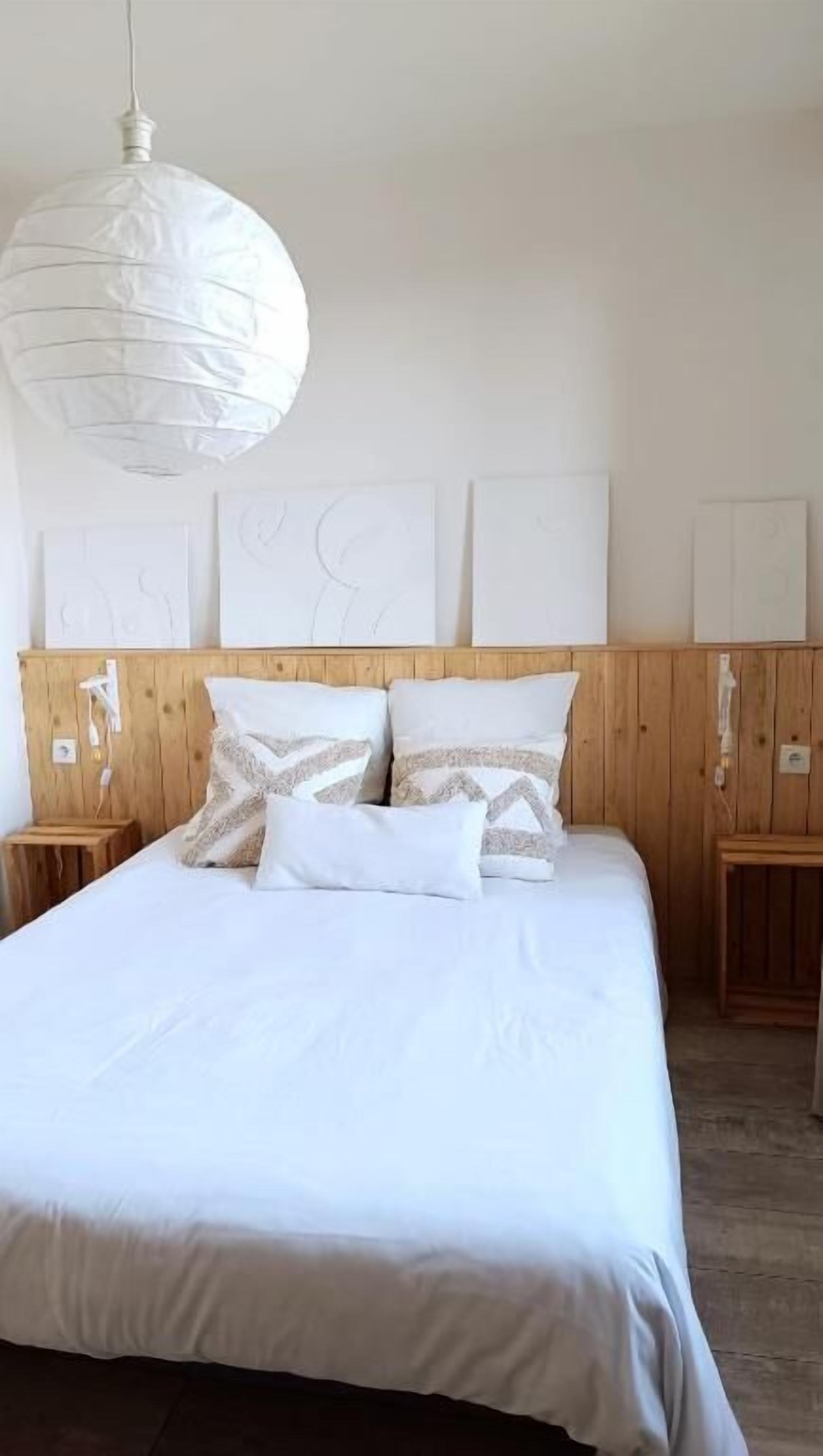 A bed with white bedding, a wooden headboard, and two bedside tables with lamps.
