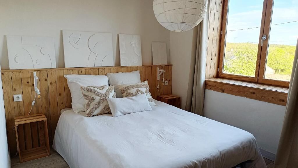 Un dormitorio con cabecera de madera, ropa de cama blanca y un cuadro abstracto en la pared.