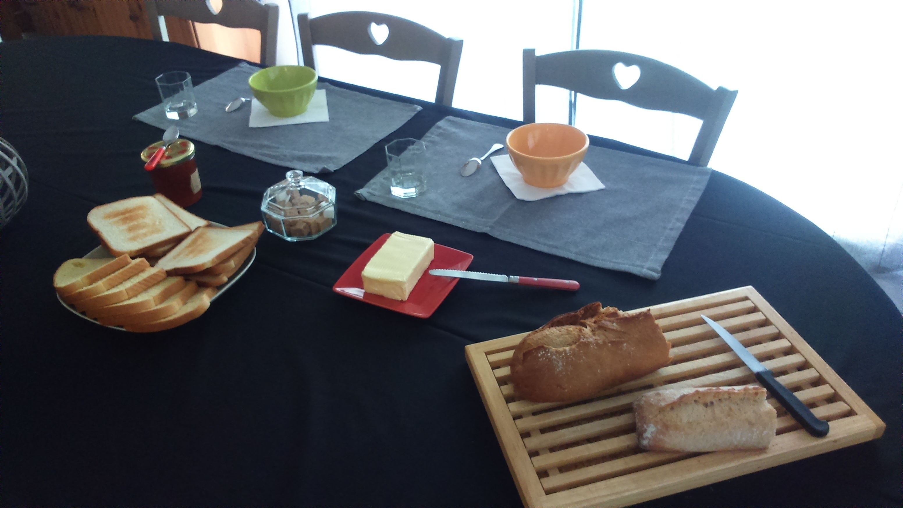 Et bord dækket med brød, smør, marmelade og en kniv.