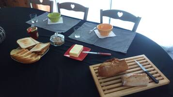 Una mesa servida con pan, mantequilla, mermelada y un cuchillo.