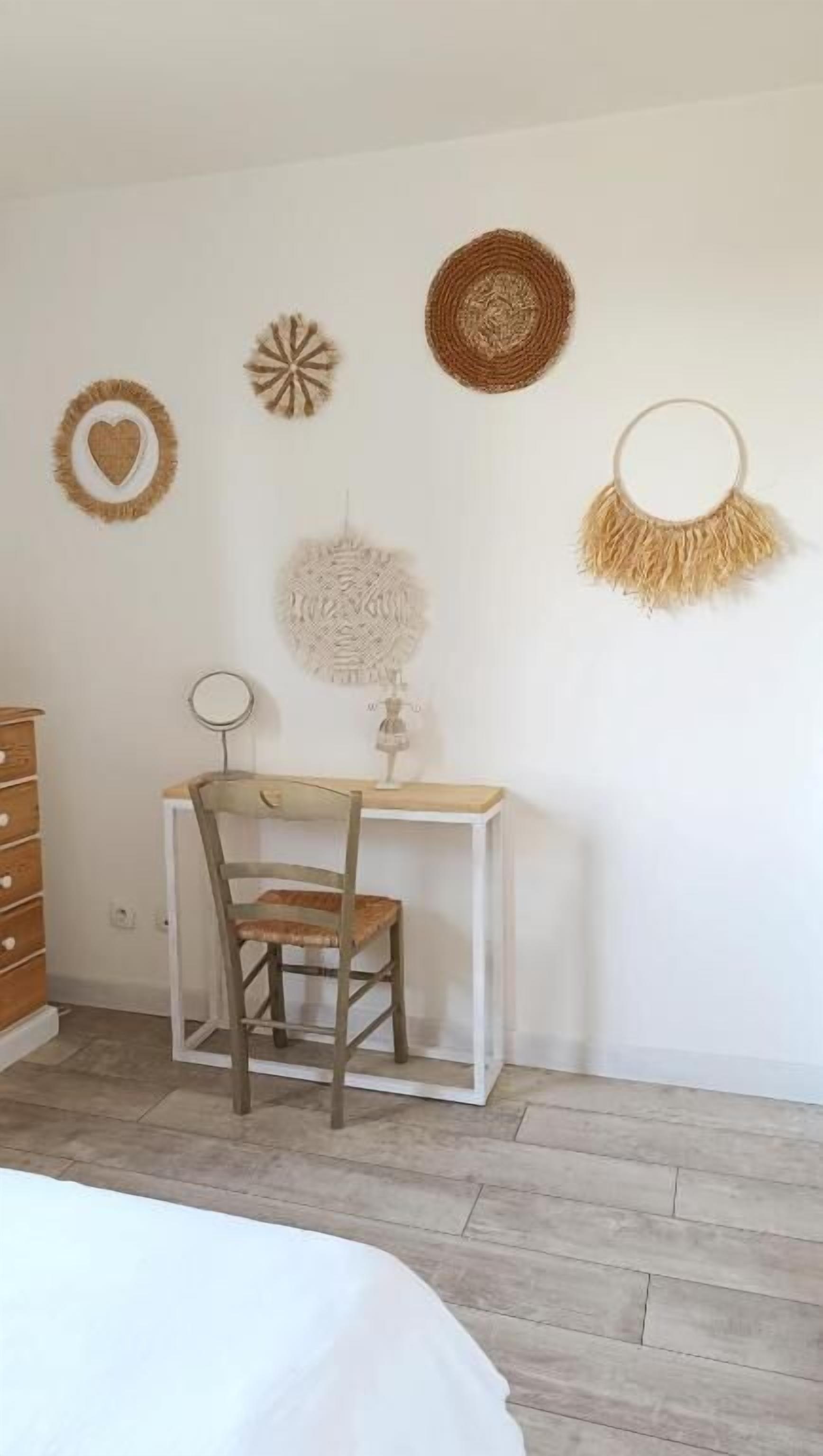Een slaapkamer met een bed, een houten dressoir, een bureau met stoel, en decoratie aan de muur.