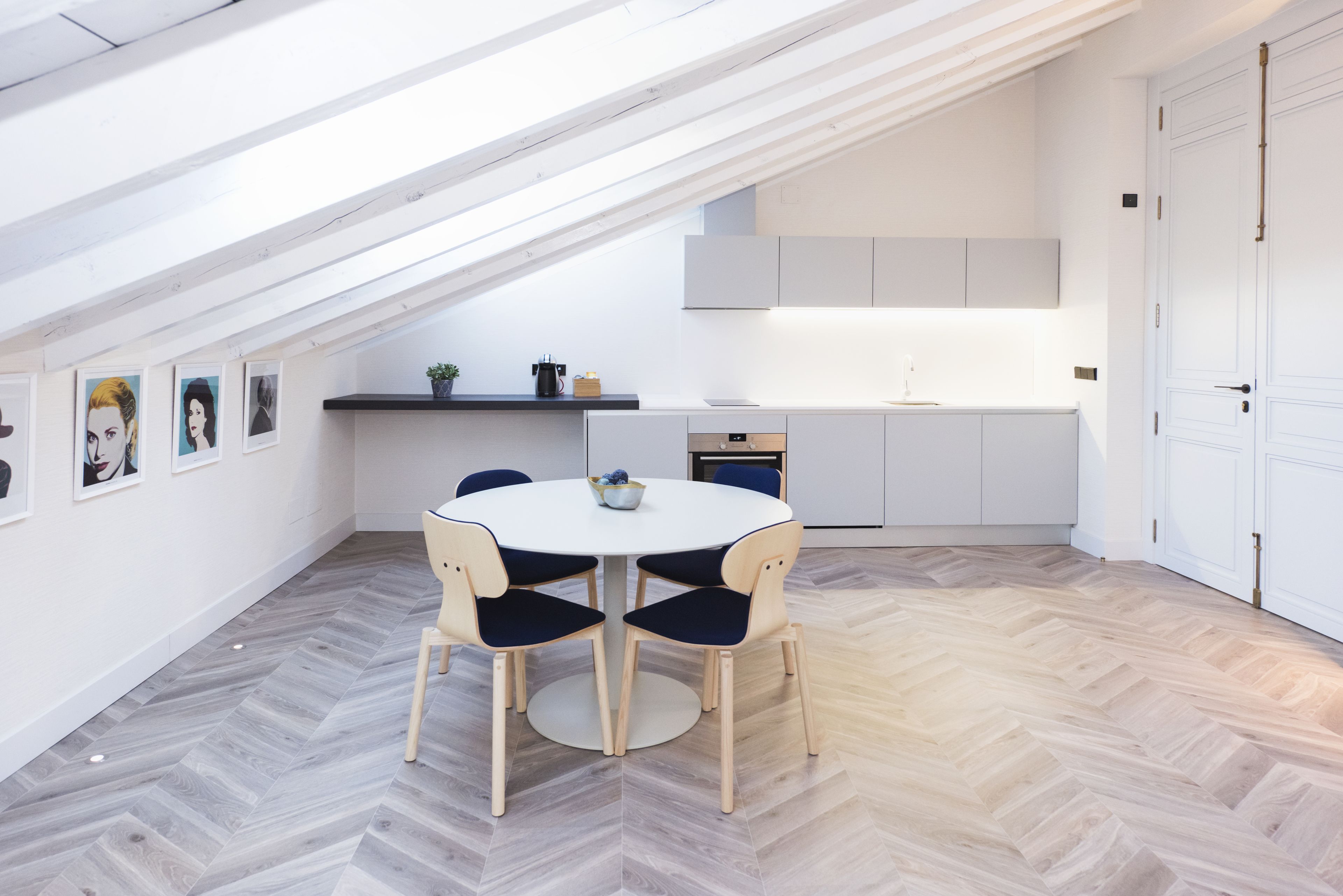 Une cuisine moderne avec une table à manger ronde et des chaises, un four encastré et un plan de travail blanc.