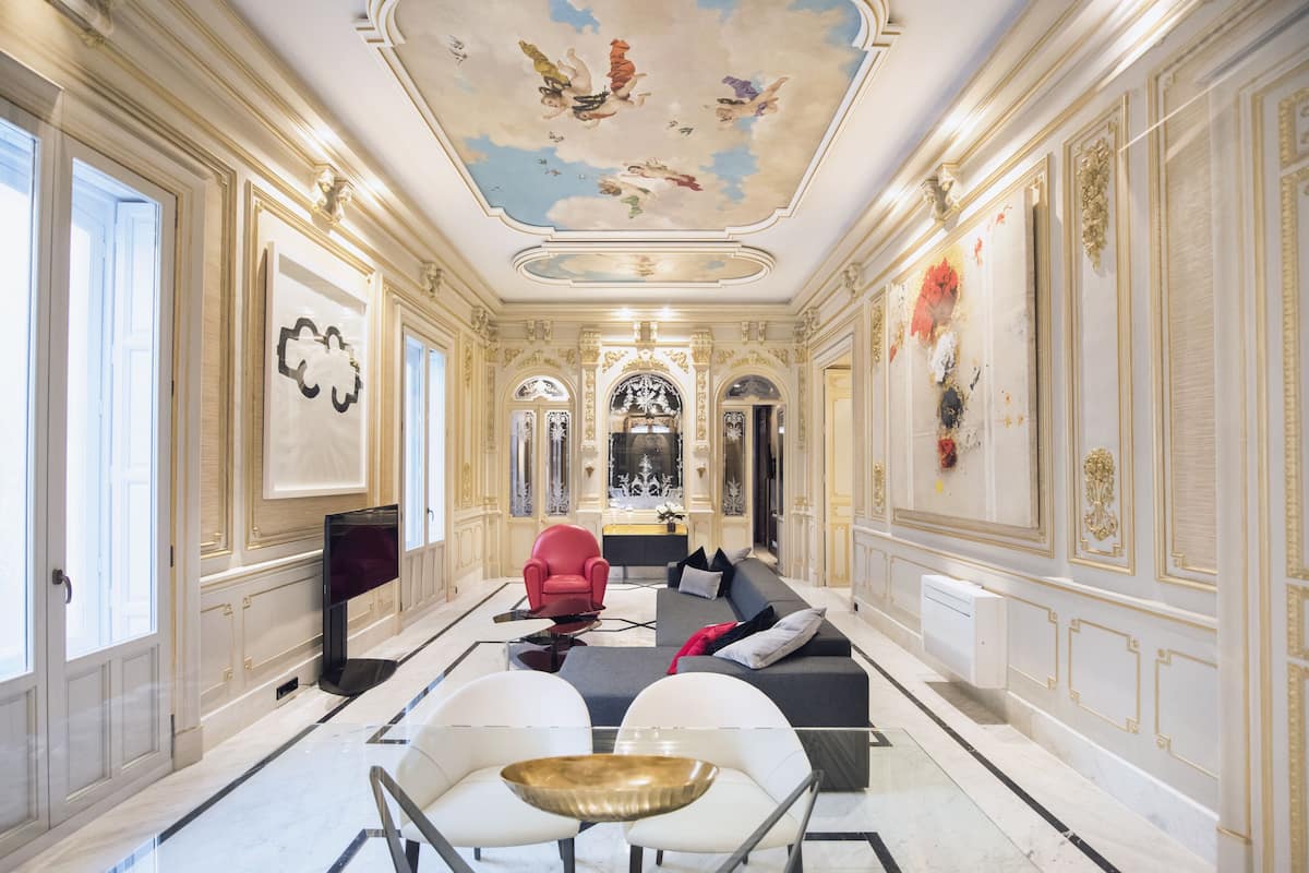 A luxurious room with a marble floor, a red armchair, a sofa, and a large white table.