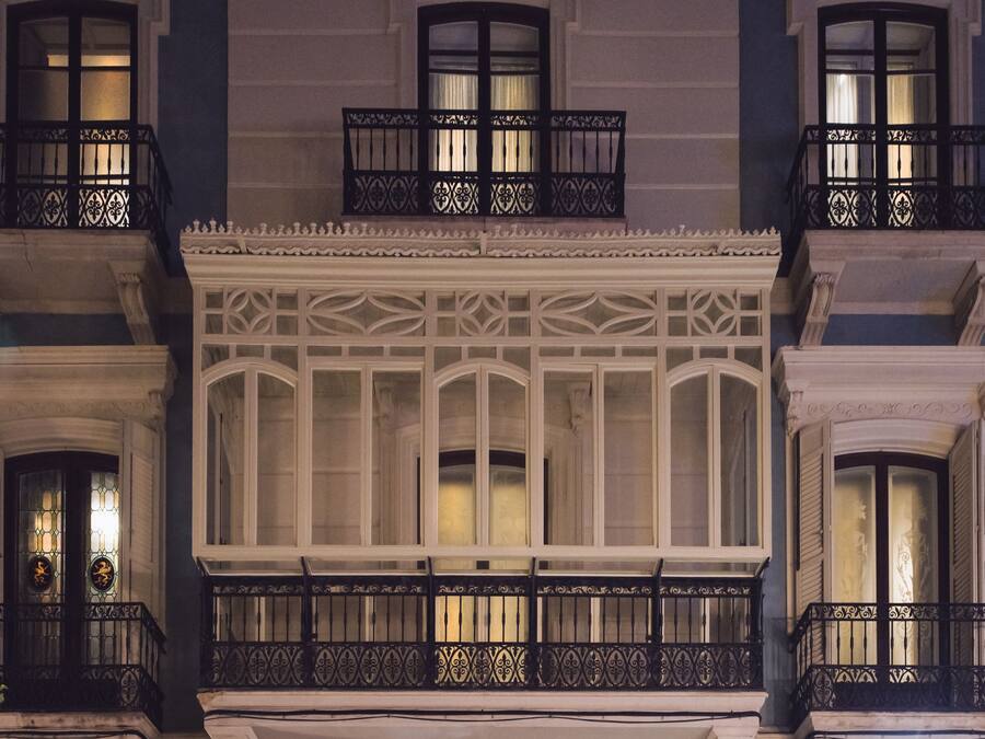 A building facade with ornate balconies, large windows, and a decorative entrance arch.
