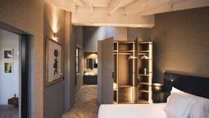 Une chambre d’hôtel moderne dotée d’un grand lit, d’un dressing et d’une salle de bain avec un miroir et un lavabo.