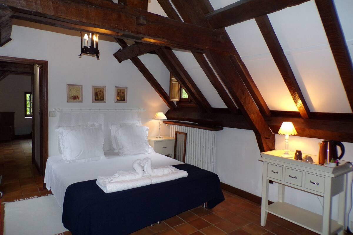 Un dormitorio con cama, mesitas de noche y vistas al exterior a través de una ventana.