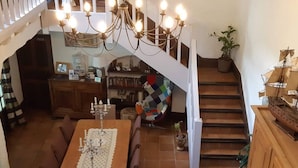 A dining area with a wooden table set for six, a chandelier, and a staircase leading to an upper level. - Le Moulin de Bénédicty (Saint Gery-Vers)