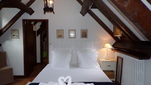 A bedroom with a bed, a nightstand, a lamp, and a wooden ceiling structure. - Le Moulin de Bénédicty (Saint Gery-Vers)