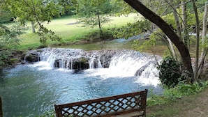 A bench overlooking a waterfall in a natural setting. - Le Moulin de Bénédicty (Saint Gery-Vers)
