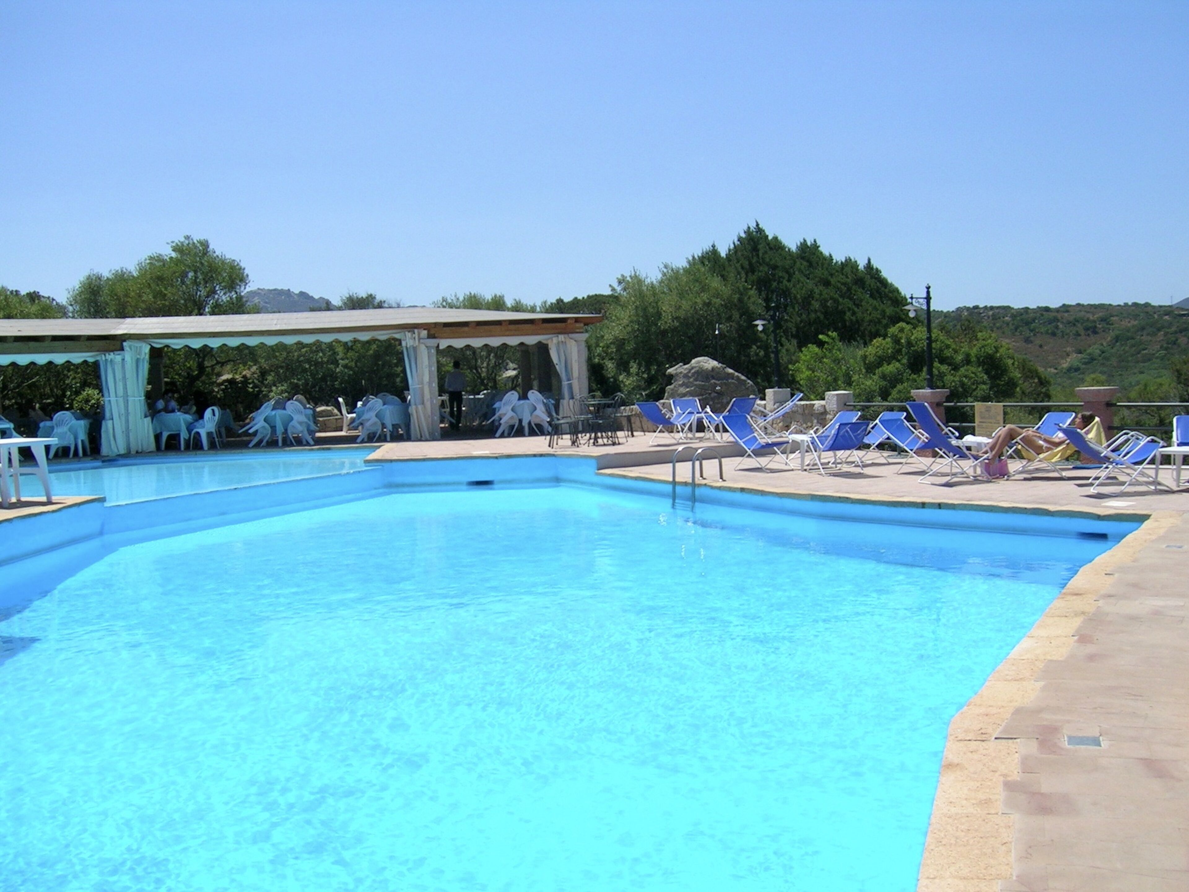 A swimming pool with lounge chairs and a covered seating area.