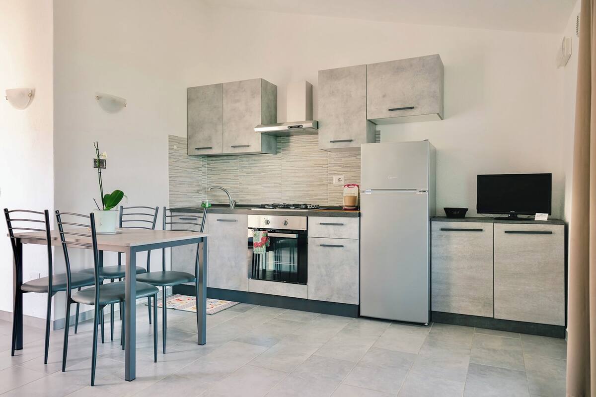 Una cocina moderna con gabinetes grises, horno empotrado y refrigerador.