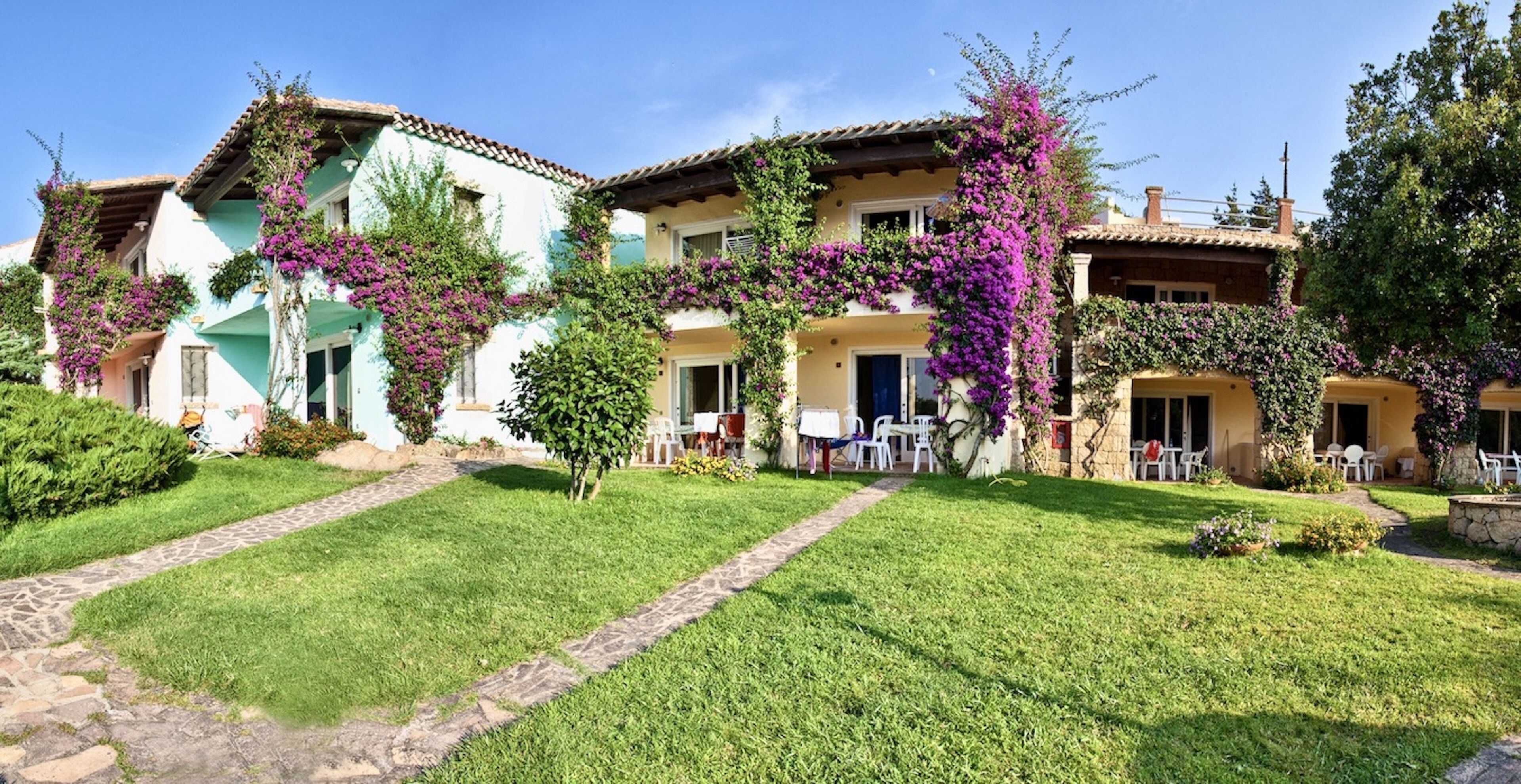A traditional building with multiple balconies, a stone pathway, and a well-maintained lawn.