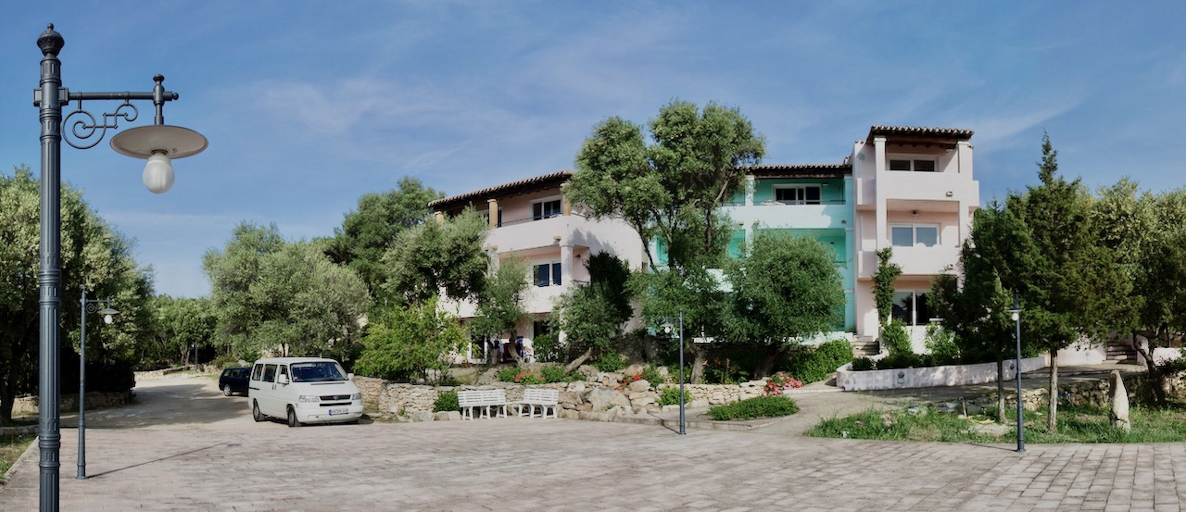 Una zona residencial con casas de dos pisos, un camino de entrada pavimentado y una furgoneta blanca estacionada.