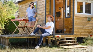 A wooden cabin with a porch, a table, and a bench.