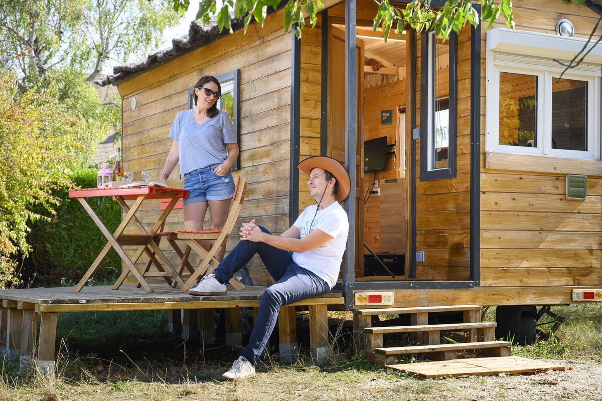 Une cabane en bois avec une véranda, une table et un banc.