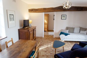 Una habitación con una mesa de comedor de madera, un sofá, un televisor y una cama.