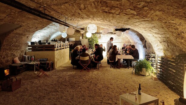 An underground dining area with rustic stone walls, wooden tables, and a cozy atmosphere.