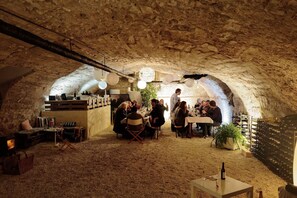 Un espace de restauration souterrain aux murs de pierre rustiques, aux tables en bois et à l’ambiance chaleureuse.