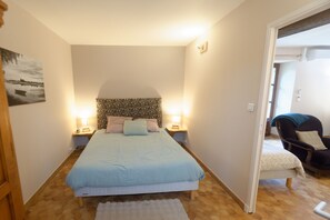 A bedroom with a bed, two bedside lamps, a chair, and a door leading to another room. - La Boisselée (Saint-Dye-sur-Loire)