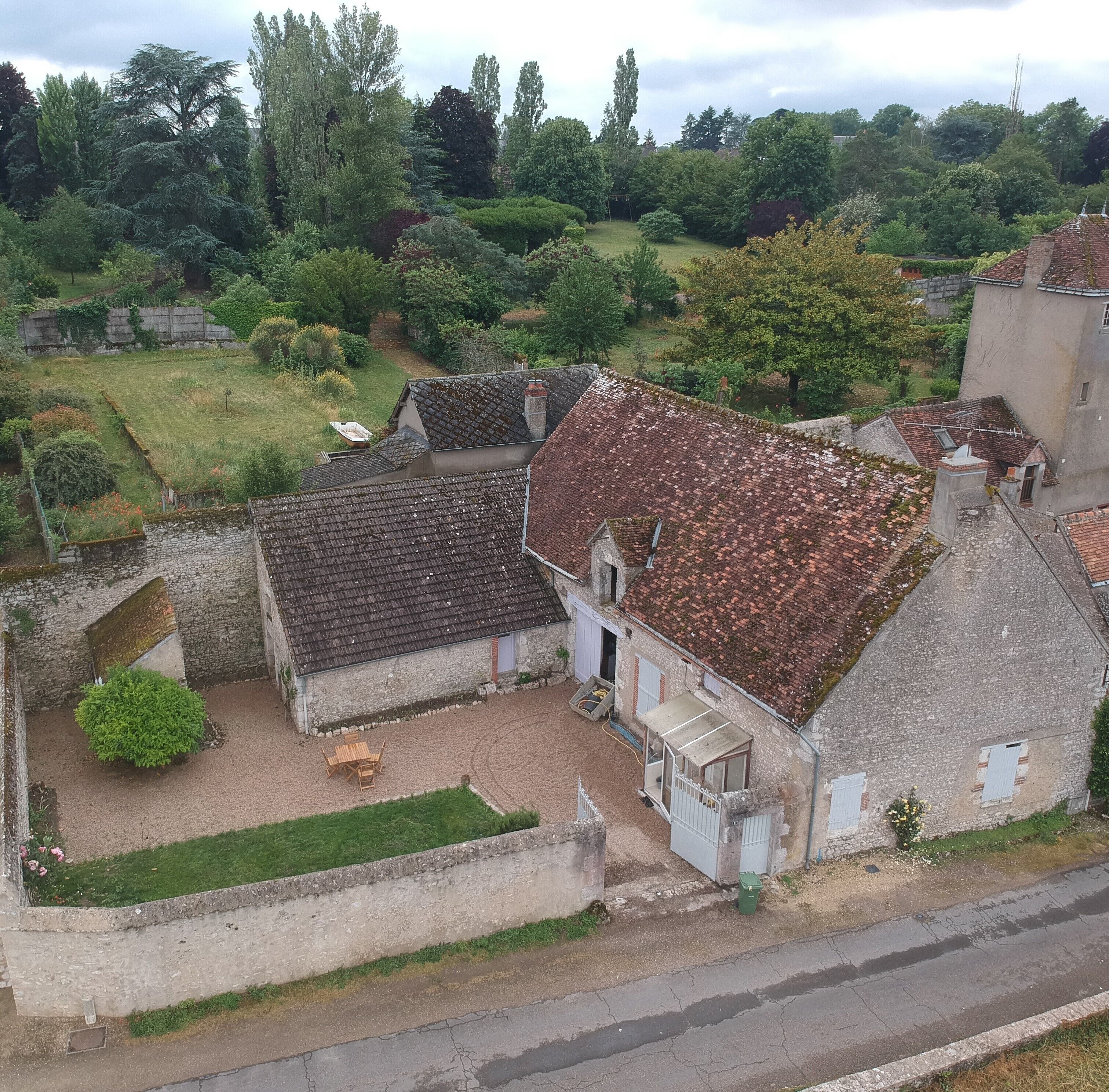 Une maison de campagne avec un toit en tuiles, un petit jardin et une allée pavée.