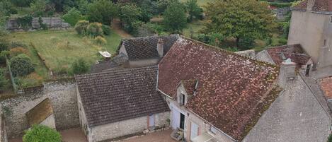 Une maison de campagne avec un toit en tuiles, un petit jardin et une allée pavée.