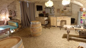 A rustic, cave-like interior with a wooden bar area, a large barrel, and a cozy seating area.