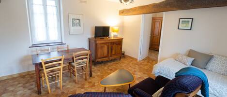 Una habitación con una mesa de comedor, sillas, un sofá, un televisor y una lámpara.