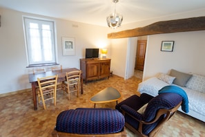 A room with a dining table, chairs, a sofa, a television, and a lamp. - La Boisselée (Saint-Dye-sur-Loire)