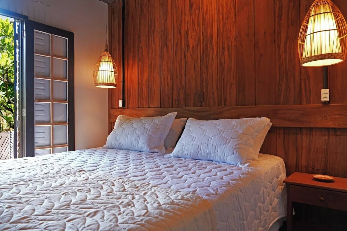 Ein Schlafzimmer mit einem großen Bett, Holzvertäfelung an den Wänden und zwei Wandleuchten.