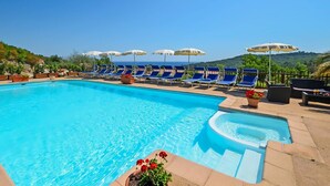 A swimming pool with lounge chairs and umbrellas, surrounded by greenery and hills. - Résidence SerenAmore (Conca)