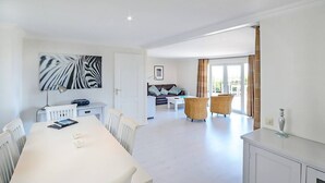 A spacious living area with a white dining table, a sofa, and wicker chairs. - Résidence SerenAmore (Conca)